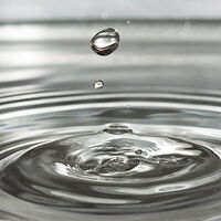 Bild eines in Wasser fallenden Wassertropfens, der einen Eindruck hinterlässt